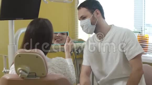 漂亮的年轻女人坐在诊所的牙科椅上医生检查口腔女人微笑视频的预览图