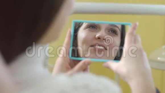 把坐在牙医椅上的年轻女性的肖像特写牙医检查口腔美丽的女人微笑通过视频的预览图