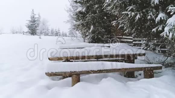 当更多的雪落下来时长凳上覆盖着雪视频的预览图