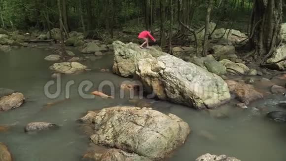 泰国KohSamui山上的NaMuang瀑布上年轻女孩在岩石上行走视频的预览图