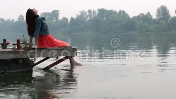 女人的双腿挂在木墩上的河里视频的预览图