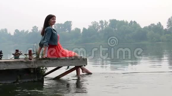 女人的双腿挂在木墩上的河里视频的预览图