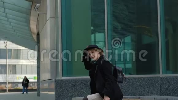 带背包散步的金发女孩在街上戴帽子视频的预览图