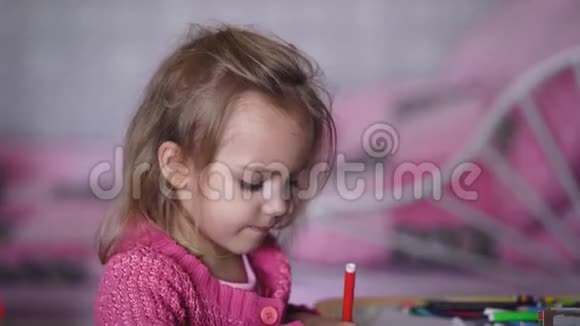 漂亮的小女孩穿着粉红色的羊毛衫在幼儿园用铅笔画插图小孩子在画画视频的预览图