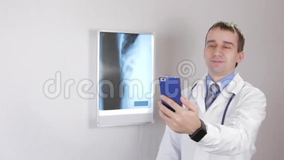 年轻男医生在电话中进行视频交流咨询白色的墙壁和带有肋骨的X光透视器视频的预览图