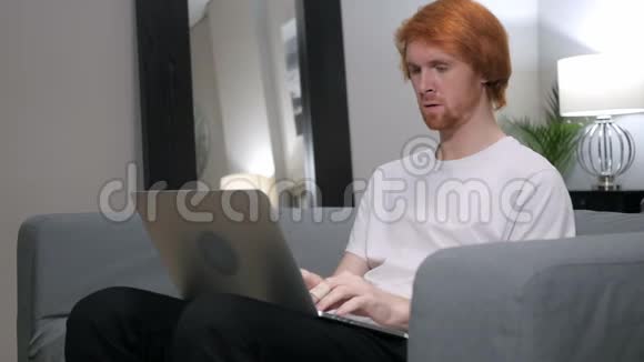 为失败而悲伤的红发男子在笔记本电脑上工作视频的预览图