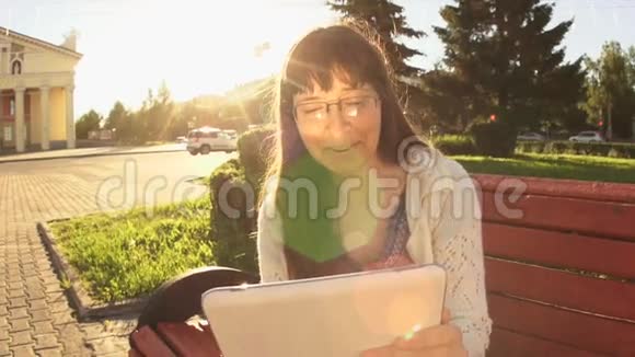 夏天日落时分一位年轻女子在长凳上放着一块白色的石碑视频的预览图