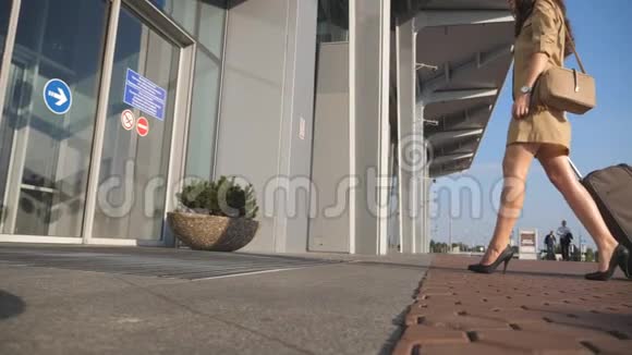 穿着高跟鞋的年轻女子带着手提箱走到机场入口处商务小姐和她一起去机场视频的预览图