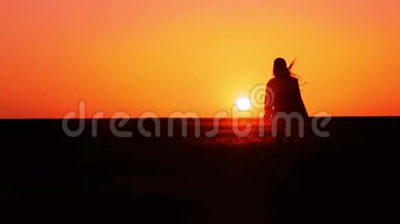 女孩在日落时跑到地平线上视频的预览图