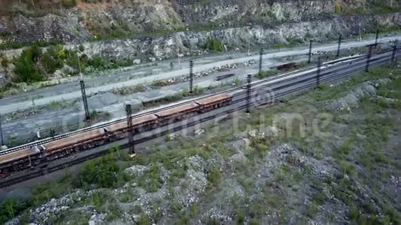 内燃机车在石灰石开采采石场的背景下推着装满碎石的自卸汽车视频的预览图
