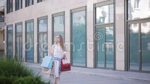 一个漂亮的女孩带着商店里的包裹散步喝咖啡成功的购物视频的预览图