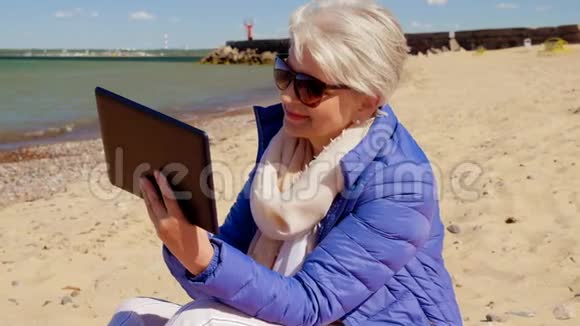 海滩上有平板电脑的老太太视频的预览图