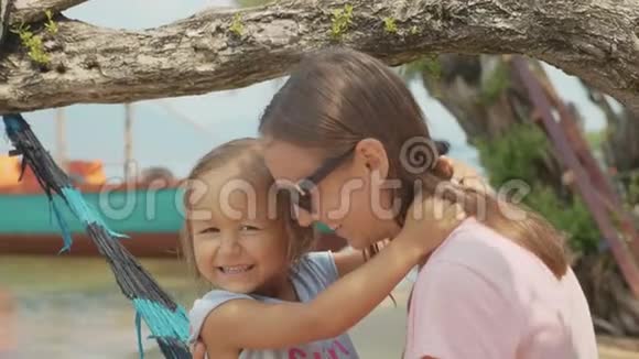 妈妈和她可爱的小女儿在沙滩吊床上玩视频的预览图