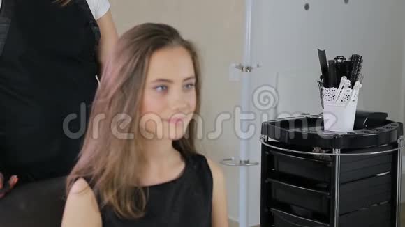 发型师理发师为穿白衣服的少女准备理发室视频的预览图