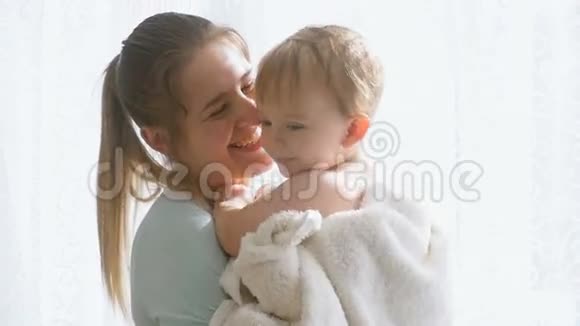 美丽微笑的母亲在大窗户上拥抱并与婴儿交谈的慢镜头视频的预览图