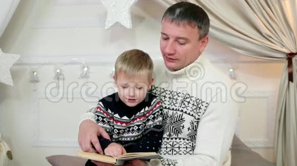 爸爸和小儿子一起读一本书一家人在家读书一个父母和一个孩子读一个故事好视频的预览图