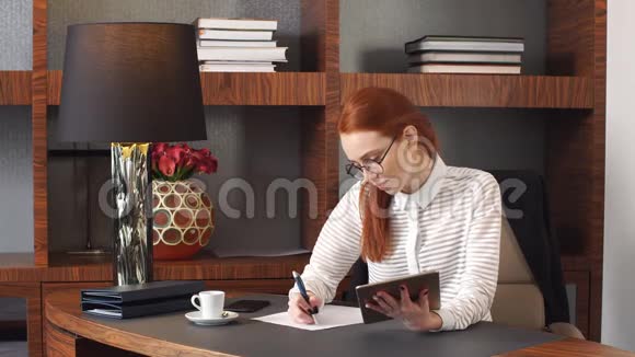 时髦的红发女孩在家里工作视频的预览图