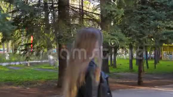 年轻漂亮的女孩正在公园里散步女孩微笑是因为天气很好视频的预览图