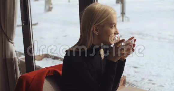 年轻的金发女孩在餐馆里喝茶视频的预览图
