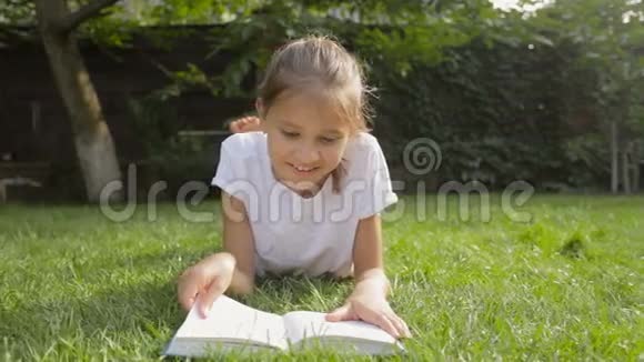 多莉在后院草地上看书脸上带着微笑的黑发女孩视频的预览图