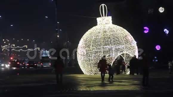 小镇广场的圣诞装饰一个巨大的发光球人们走在傍晚一辆马车走着一种喜庆的心情视频的预览图