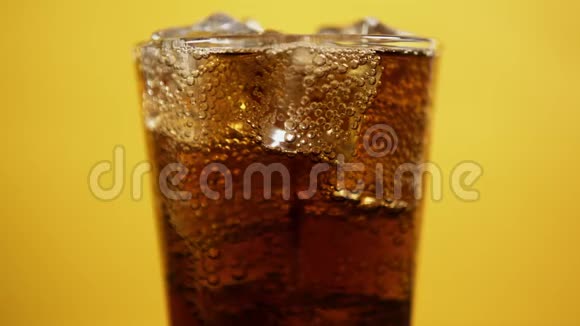 一杯装满冰块的可乐饮料可乐汽水黄色背景视频的预览图