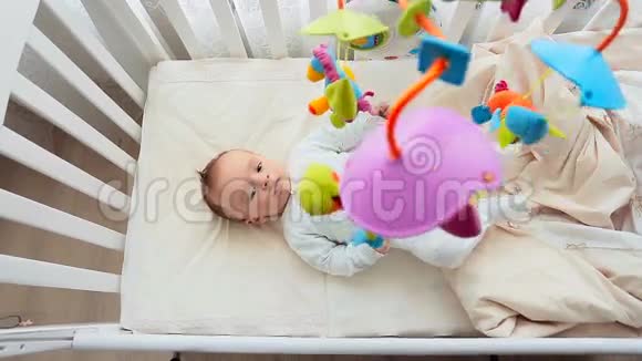 顶部的照片可爱的婴儿与其他躺在婴儿床和看旋转移动视频的预览图