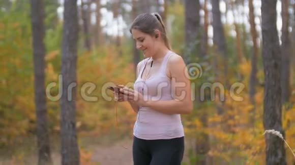 4森林慢跑时年轻的微笑女子听音乐的K镜头视频的预览图