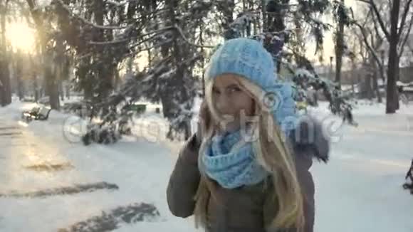 穿着温暖的帽子和围巾在冬季公园散步的年轻漂亮女士视频的预览图