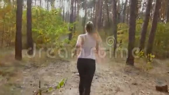 4K镜头显示年轻女子在森林的道路上快速奔跑视频的预览图