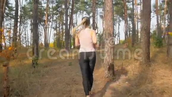 后景慢镜头活跃的年轻女子早上在森林里跑上山视频的预览图