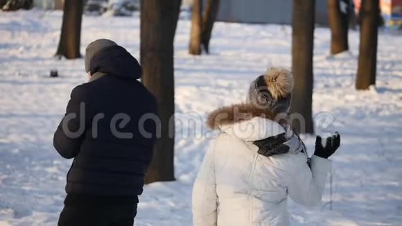 男人和女人的一对夫妇在一片白雪皑皑的冬林里互相扔雪球慢动作视频的预览图