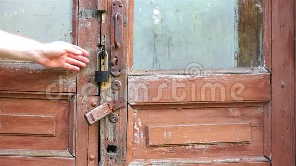 一个人一扇破旧的旧木门的铁门把手用手检查紧闭的门锁视频的预览图