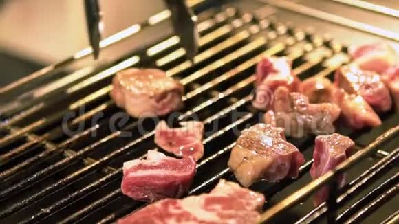 亚洲夜市一个小贩在烤架上烹制牛肉肉的慢动作视频的预览图