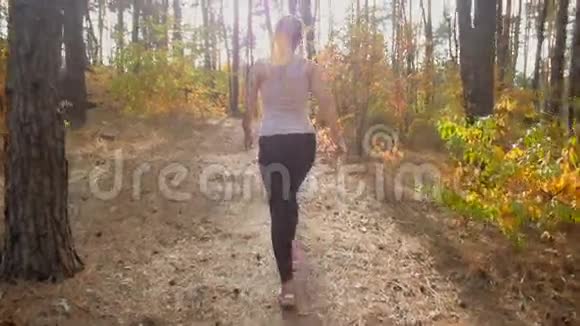 穿着运动服的年轻女子在秋林散步的慢镜头视频的预览图