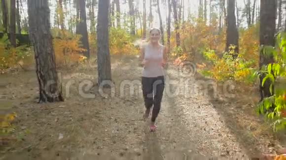 在森林中奔跑的运动妇女向太阳缓慢移动的画面视频的预览图