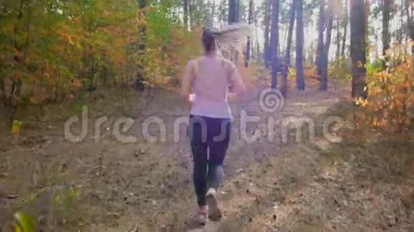 年轻女子在森林松树间奔跑的慢镜头视频的预览图