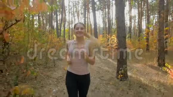在秋林慢跑的快乐微笑女子慢动作特写镜头视频的预览图