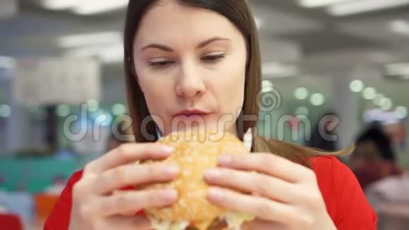 饥饿的女孩在食物场上吃汉堡包快餐店的女人咬芝士汉堡视频的预览图