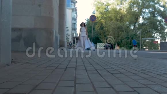 一个穿着白色西装的年轻女孩沿着河堤奔跑视频的预览图
