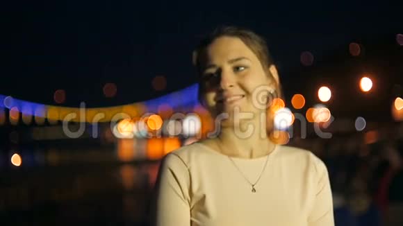 夜晚一位优雅的年轻女子在照亮的河上的桥上摆姿势视频的预览图
