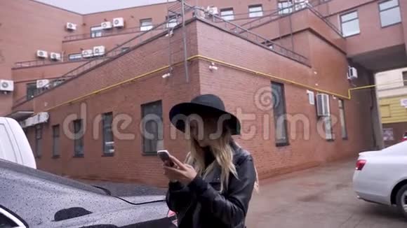 城市里的一个女孩在下雨时用智能手机她很高兴视频的预览图