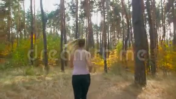 4K镜头拍摄的是在森林里慢跑的美丽微笑的女人视频的预览图