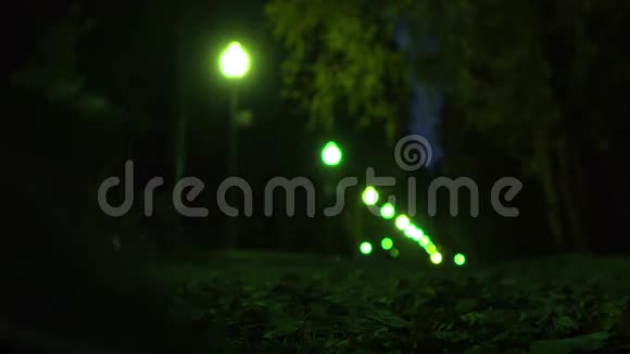 女孩穿着运动鞋走在秋天落叶的夜晚浅浅的焦点公园小巷绿波克灯4K视频视频的预览图