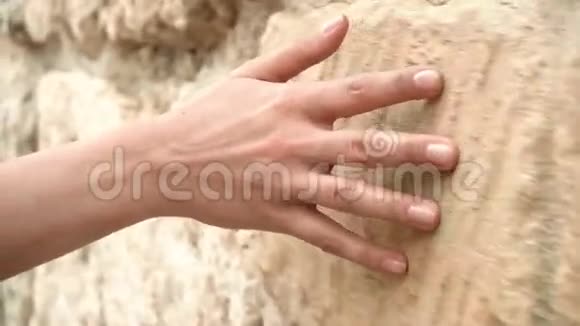 女人手移过旧石壁一直滑下去感性的触摸坚硬的石头表面视频的预览图
