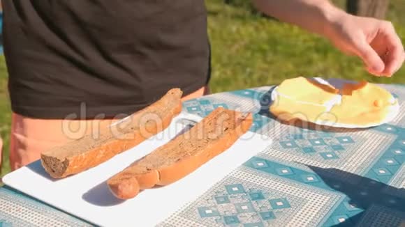 人们在野餐时用面包和奶酪做三明治把手举起来视频的预览图