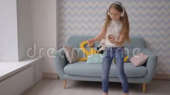 带着耳机智能手机跳舞和在家听音乐的快乐孩子视频的预览图