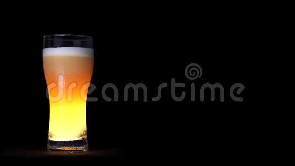 一杯金色工艺啤酒白色泡沫和移动气泡隔离在黑色背景视频的预览图