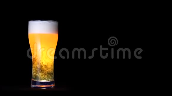 一杯金色工艺啤酒白色泡沫和移动气泡隔离在黑色背景视频的预览图