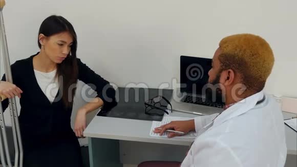 拄拐的女性患者与填写医疗表格的男性医生交谈视频的预览图